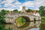 Abbildung zeigt eine schöne alte Brücke mit einem alten Dorf in England im Hintergrund